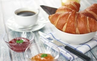 Frühstückstisch mit Kaffee, Croissant und Marmelade, wie er beim Arbeitsfrühstück aussehen könnte